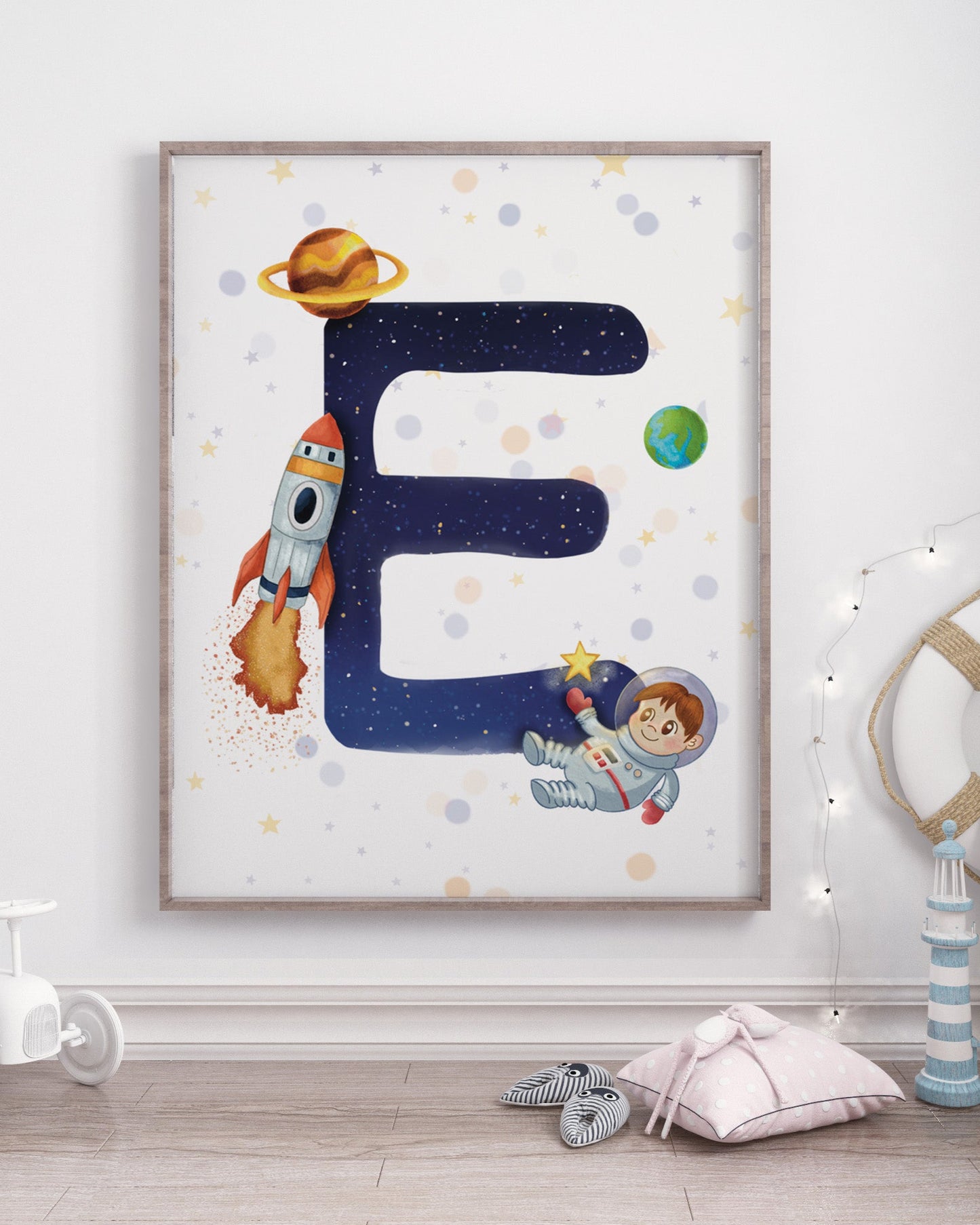 Framed children's poster with letter 'E' and space-themed illustrations in a room with toys.